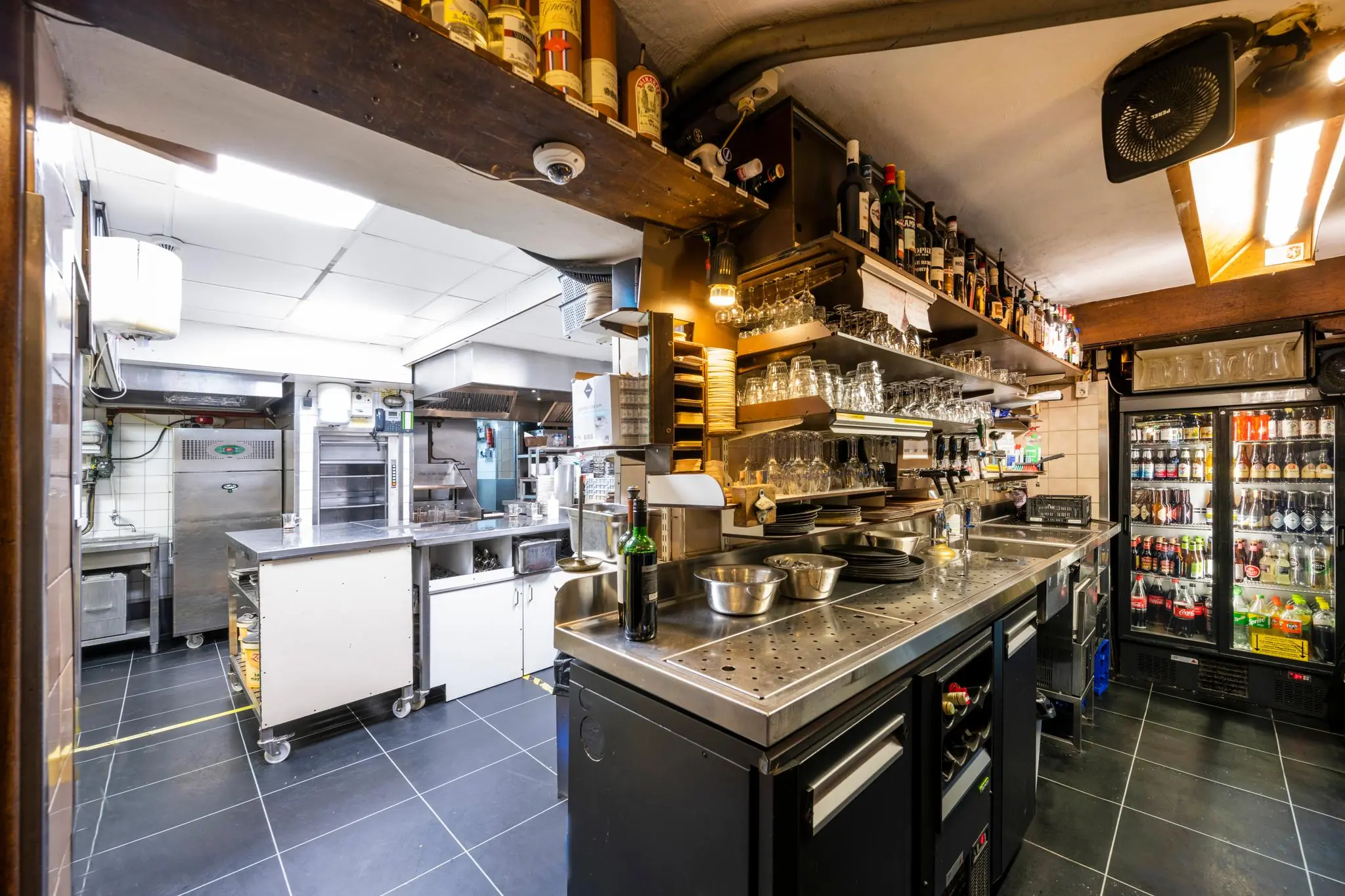 Moderne horeca-keuken en bar aan de Nieuwezijds Voorburgwal met goed uitgeruste werkstations en drankkoeling.